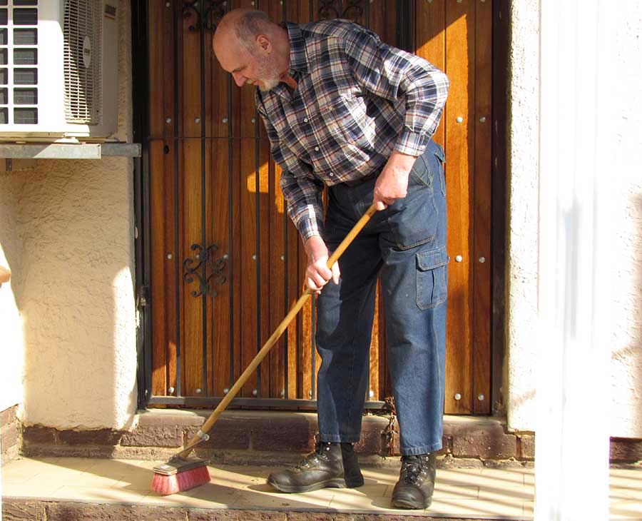 Leon sweeping the steps at the front door of his house